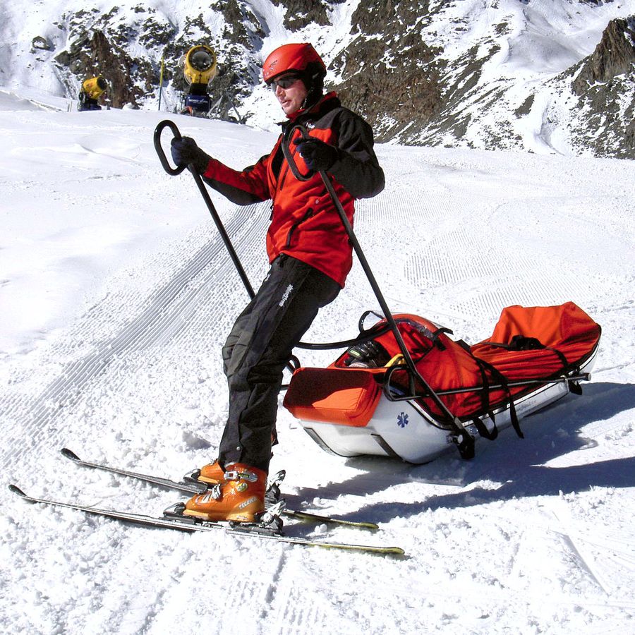 Rescue crew on skis with a sled in alpine terrain